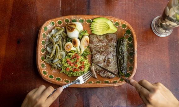 Authentic Mexican meal featuring grilled steak, avocado, and vegetables on a ceramic plate.