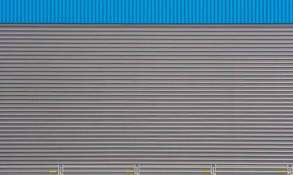 Textured metal wall with blue top section, featuring horizontal stripes and industrial design.